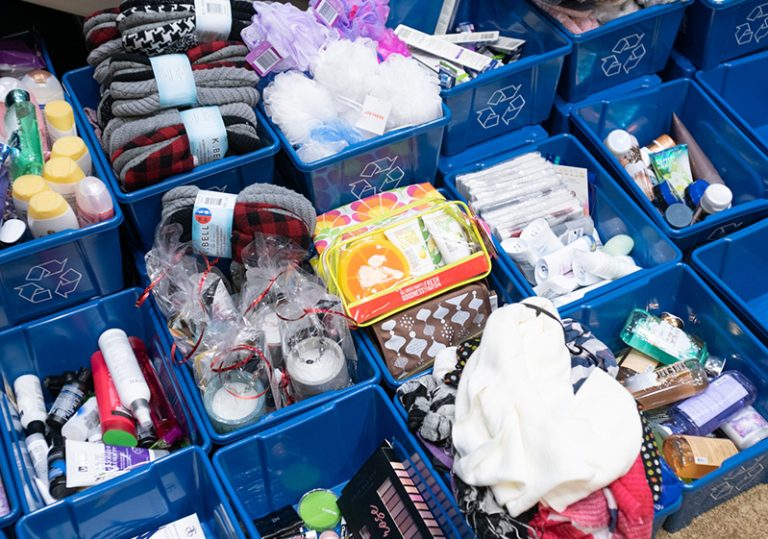 Volunteers selecting toiletries and self-care items from organized donation bins